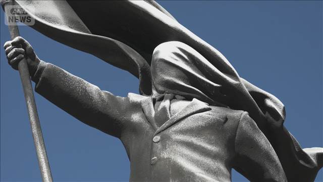 バンクシー新作「旗掲げる巨大像」顔は旗で覆われ…　自治体「撤去せず公開」