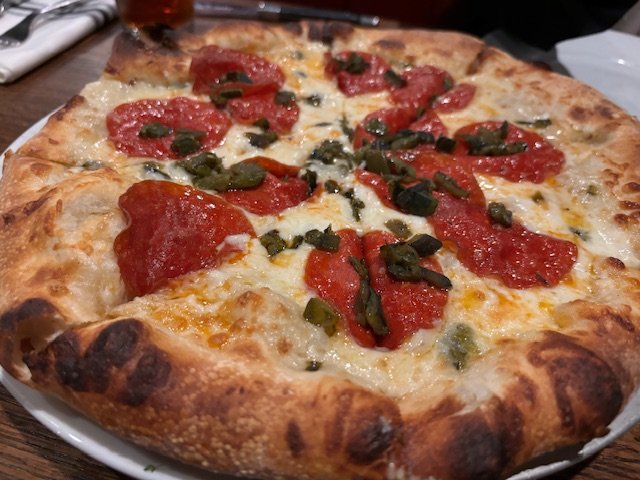コーク・アンド・ポーク・タバーンのポークチョップとビザ＝共に筆者撮影。ピザは米国でも「国民食」だ。日本では「アメリカン・ピザ」などとの言い方があるが、米国には地域によって多種多様なピザがあり、決してひとつにはくくれない。