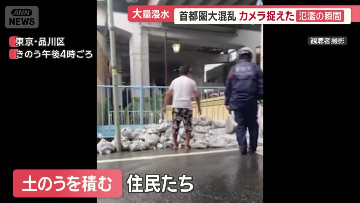 土のうを積む住民と警察官